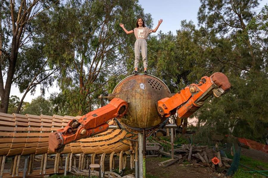 Rosie-rides-the-millipede - CERES Fair Food A child stands high on the head of the Millipede playground sculpture, CERES Brunswick