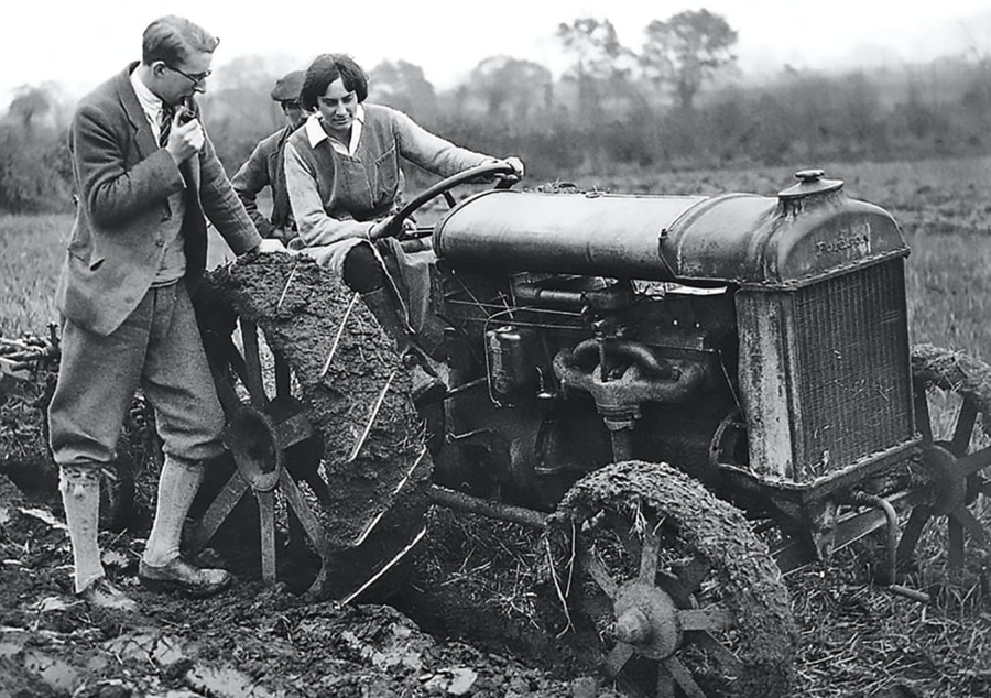Eve Balfour, black and white photo, she is driving a tractor with men talking